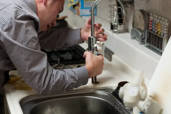a plumber fixing a kitchen sink from 24 Hr Plumbing Leander in Leander, TX - Sewer Line Clearing Services a plumber fixing a kitchen sink from 24 Hr Plumbing Leander in Leander, TX - Sewer Line Clearing Services